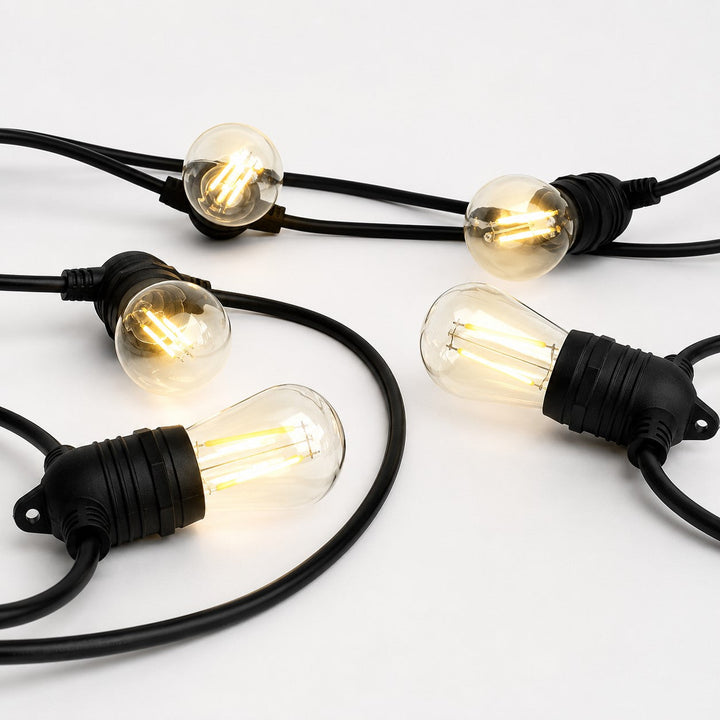 A set of outdoor string lights with clear glass globe bulbs and black cords, shown illuminated on a clean white background.